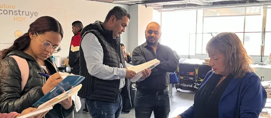 Varias personas revisan documentos en una sala con iluminación natural durante una reunión.