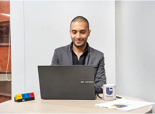 Persona frente a un portátil, con una taza de café a un lado.
