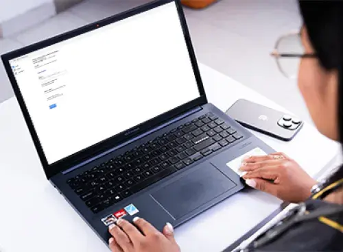 Persona frente a un portátil, con un celular a un lado.