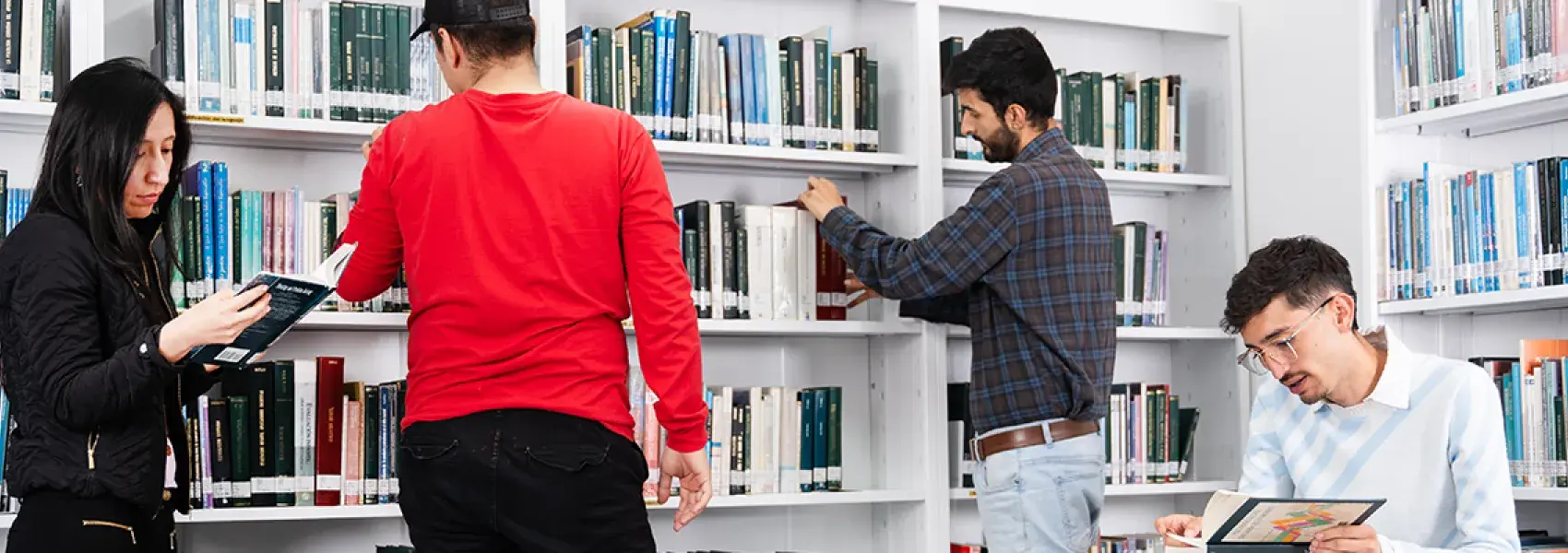 Personas leyendo libros, con varios estantes llenos de libros al fondo.